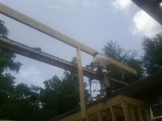 Carpenter setting a ridge beam over a new addition frame — Ice Dam Removal by Roofing Brothers in Casselton