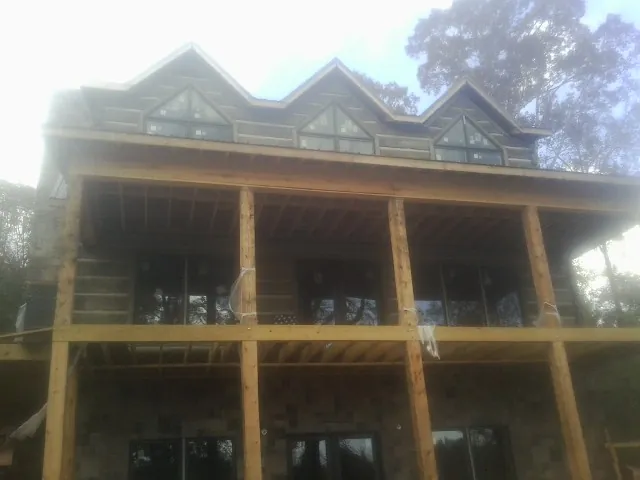 Dormers and porch framing on a large log home under construction — Roof Coating work by our crew in Casselton