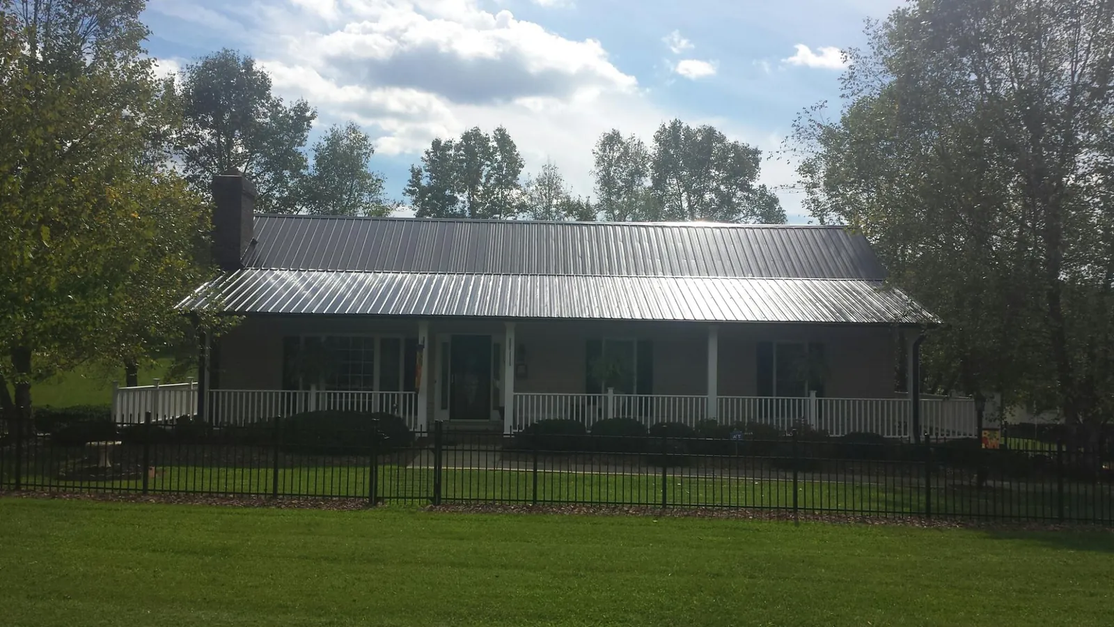 Gray metal roof on a brick ranch with a full width front porch — Gutter Guard Installation work by our crew in Casselton