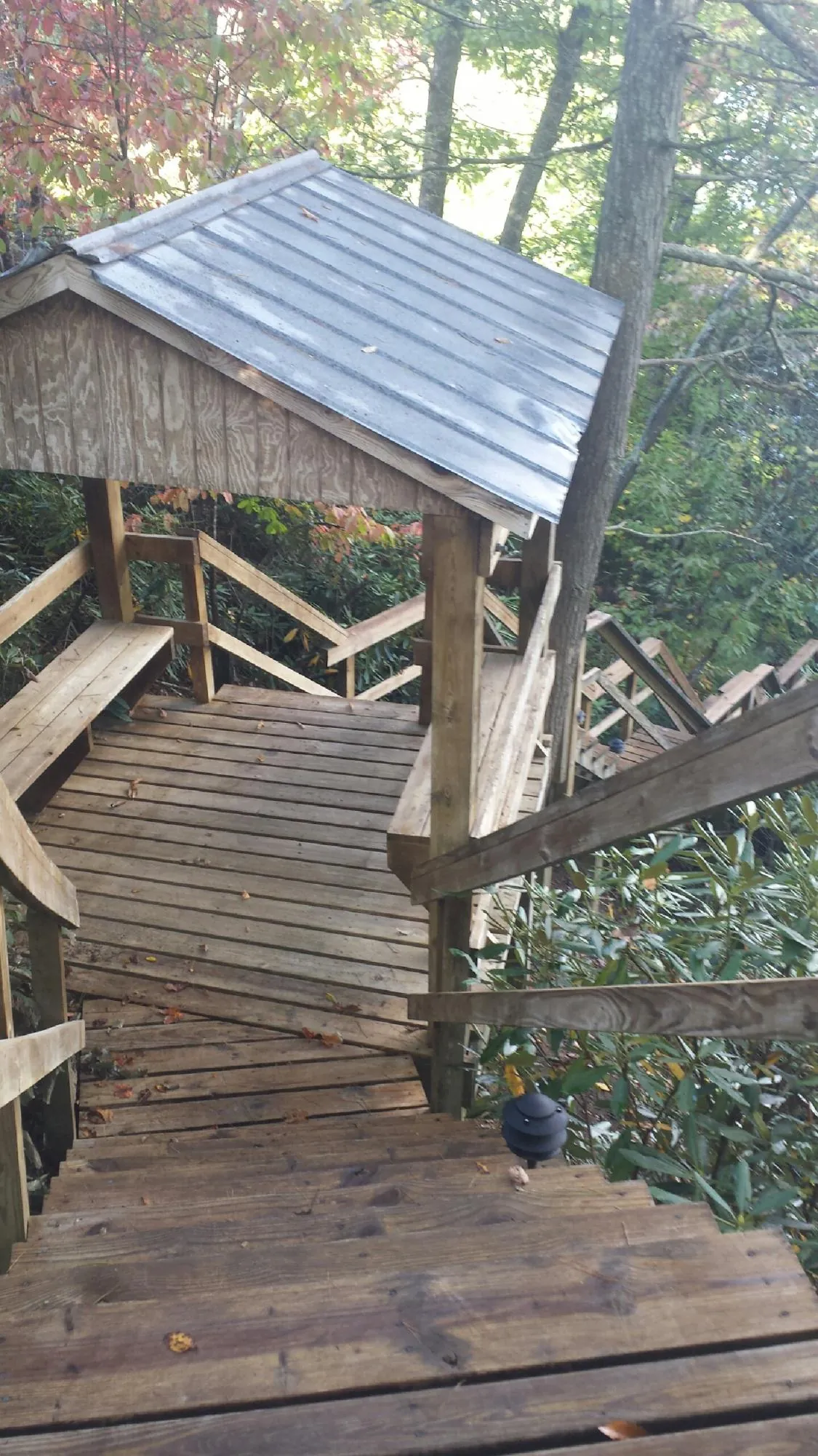 Metal roofed shelter over wooden steps on a wooded walkway — Skylight Repair & Installation work by our crew in Casselton
