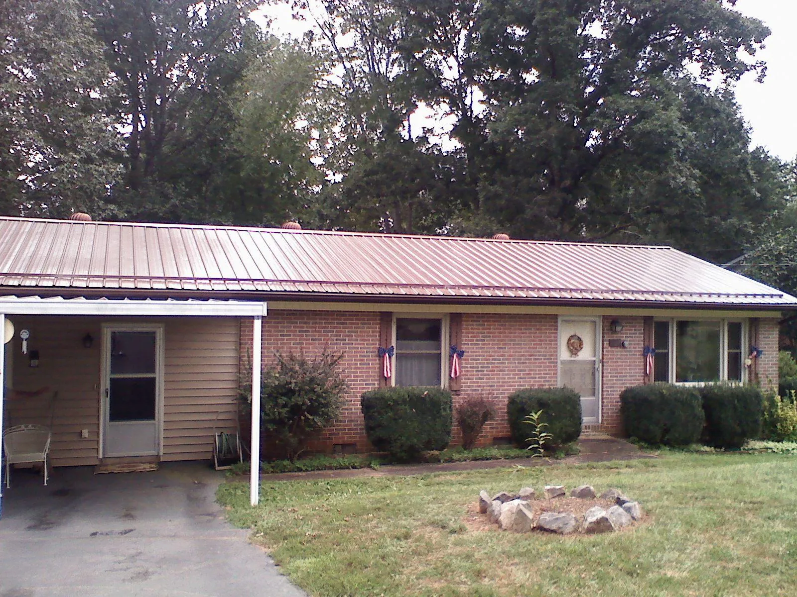 Bronze metal roof and carport on a brick ranch home — Roof Repair work by our crew in Casselton
