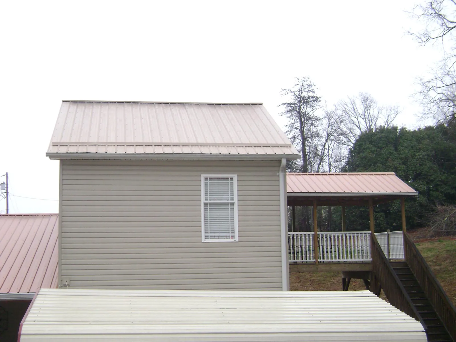 Tan metal roofs on a two story addition and attached porch, from a Roof Replacement job in Casselton