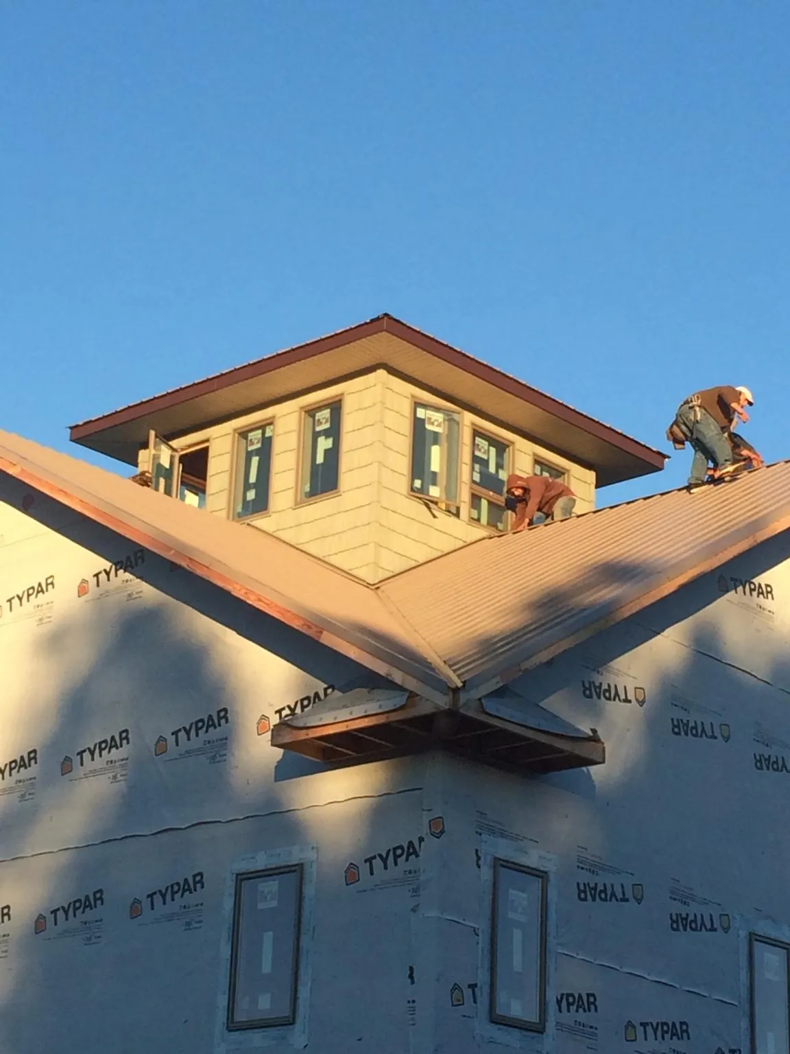 Roofers working around a rooftop cupola on a new metal roof at sunset — Roof Waterproofing in Casselton by Roofing Brothers